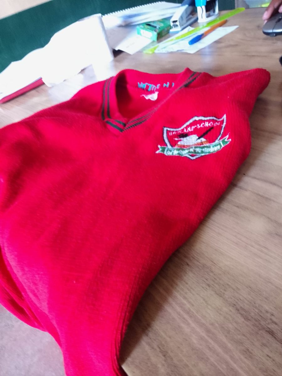 School crest embroidered on a red school sweater, Kenya